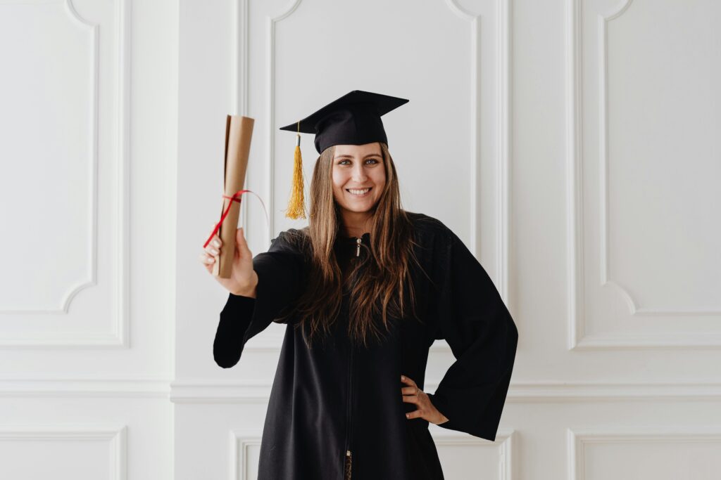 Smiling young woman in graduation attire holding diploma, showcasing academic success.
