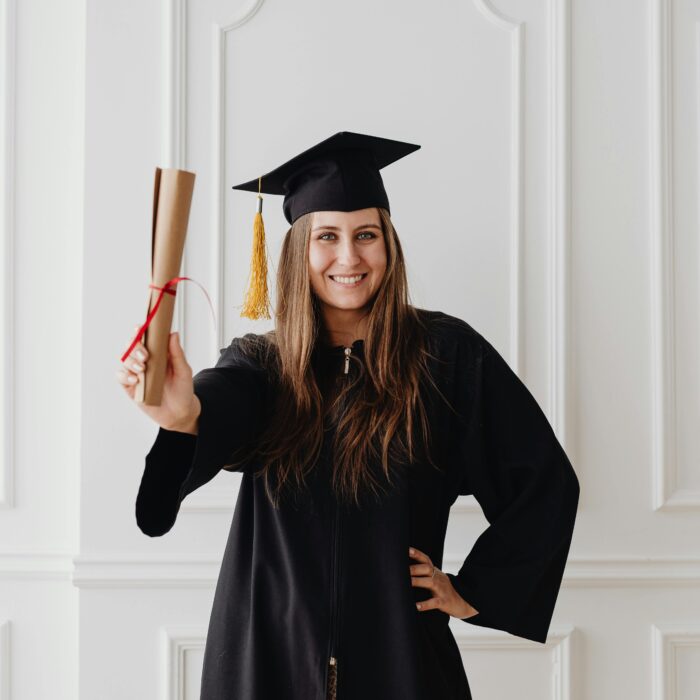 Smiling young woman in graduation attire holding diploma, showcasing academic success.